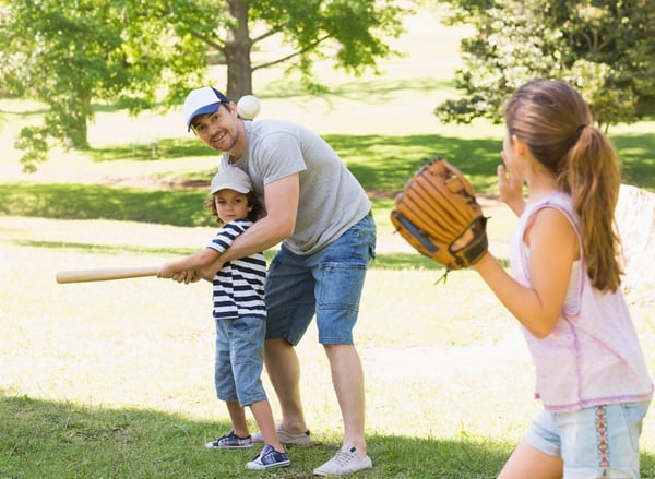 Family of three playing baseball in the park-1