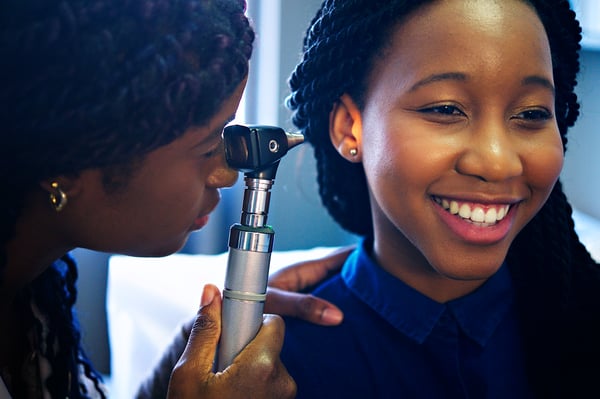 Young Black Woman Getting Ear Checked by Black Woman Doctor - iStock-1124735714